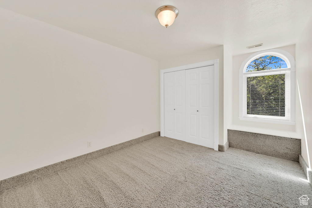 Unfurnished bedroom with carpet flooring, a closet, and baseboards