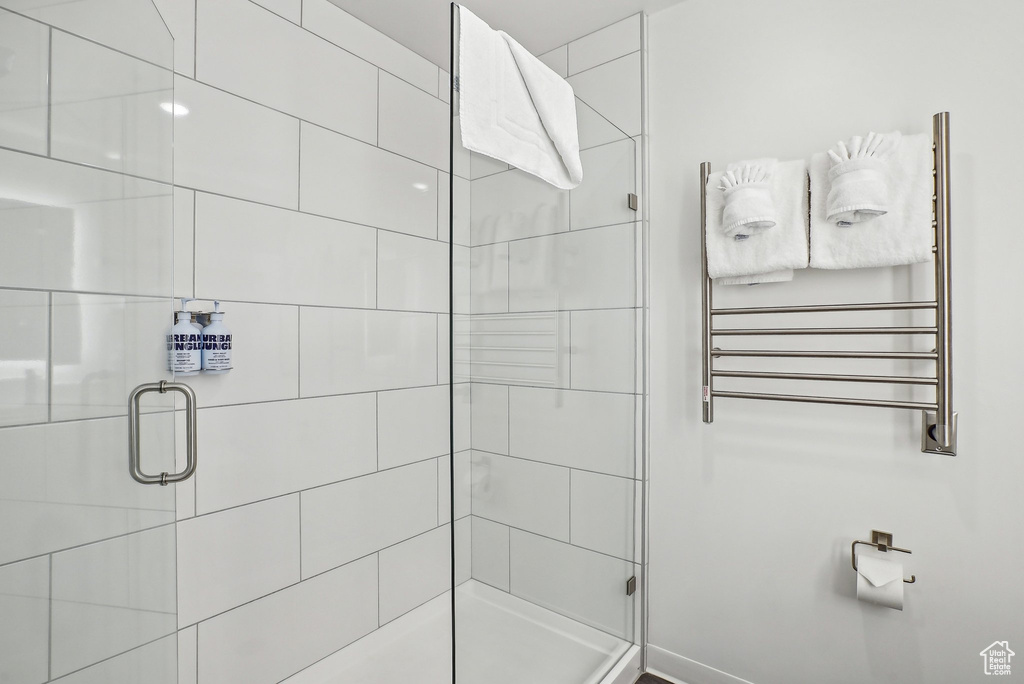 Full bathroom with radiator heating unit, a stall shower, and a towel warming rack