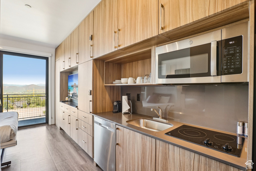 Kitchen with stainless steel appliances, a sink, light brown cabinets, dark countertops, and a mountain view