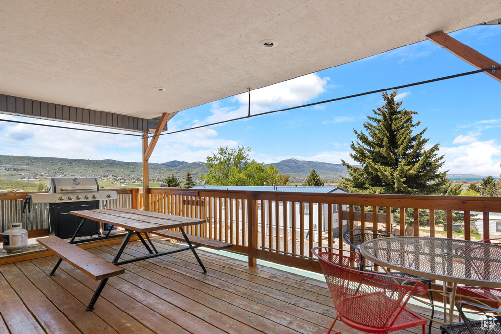 Deck with outdoor dining area, a mountain view, and grilling area