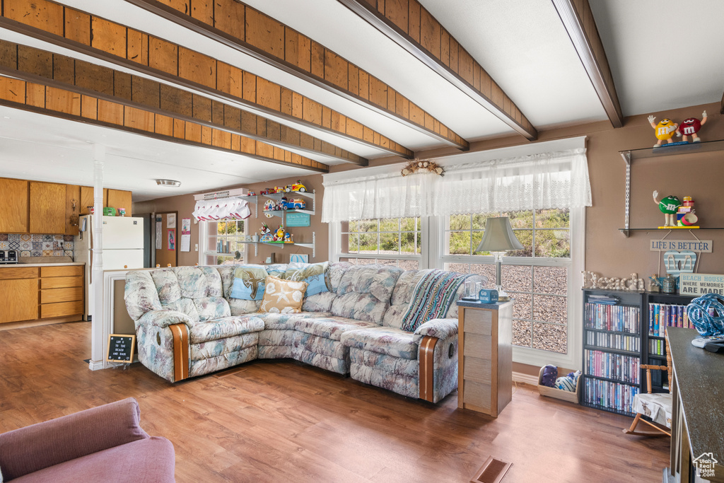 Living area featuring beam ceiling, plenty of natural light, and wood finished floors
