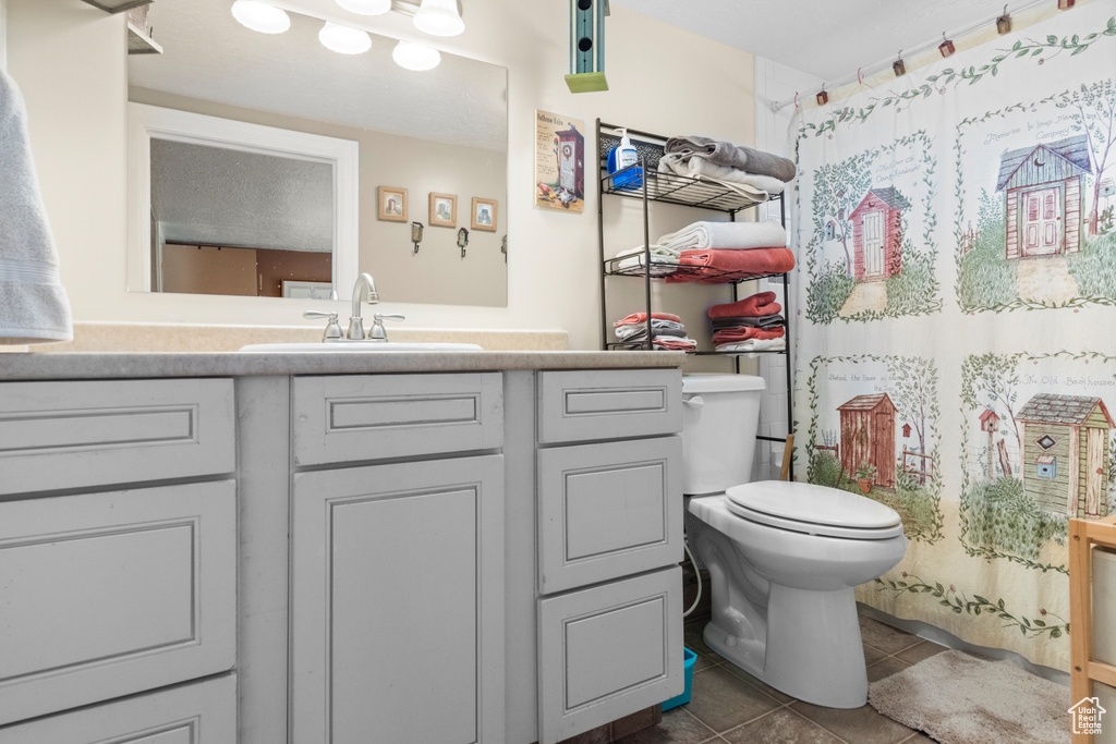 Bathroom featuring tile patterned flooring, toilet, vanity, and curtained shower