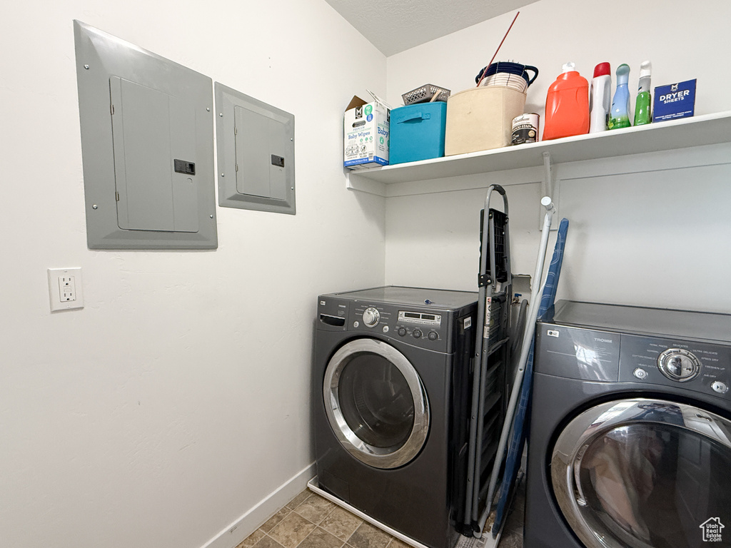 Laundry room with electric panel, washing machine and clothes dryer, and baseboards