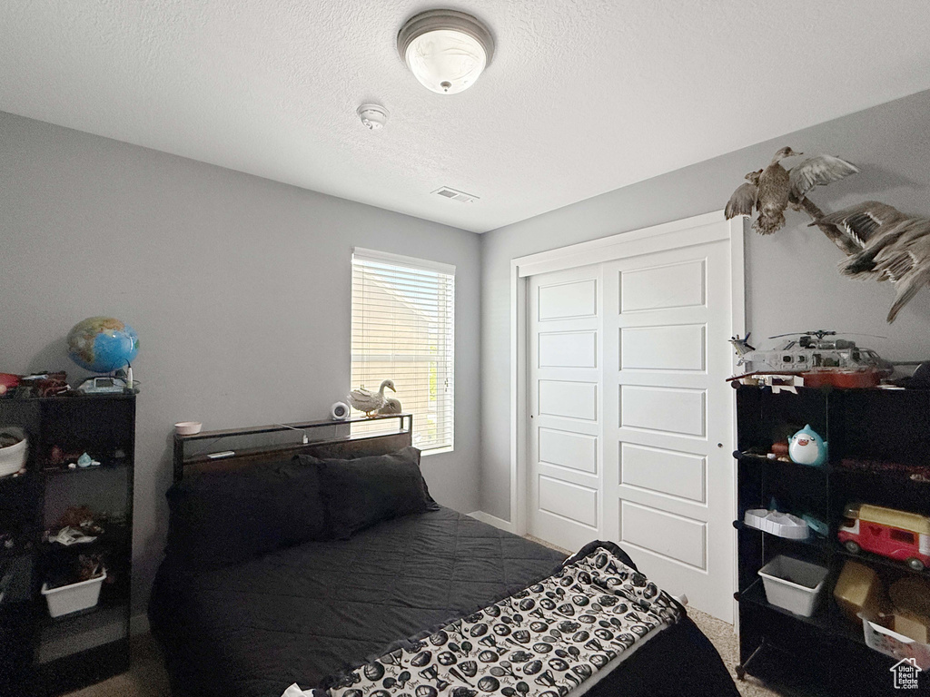 Bedroom featuring a closet, a textured ceiling, and carpet