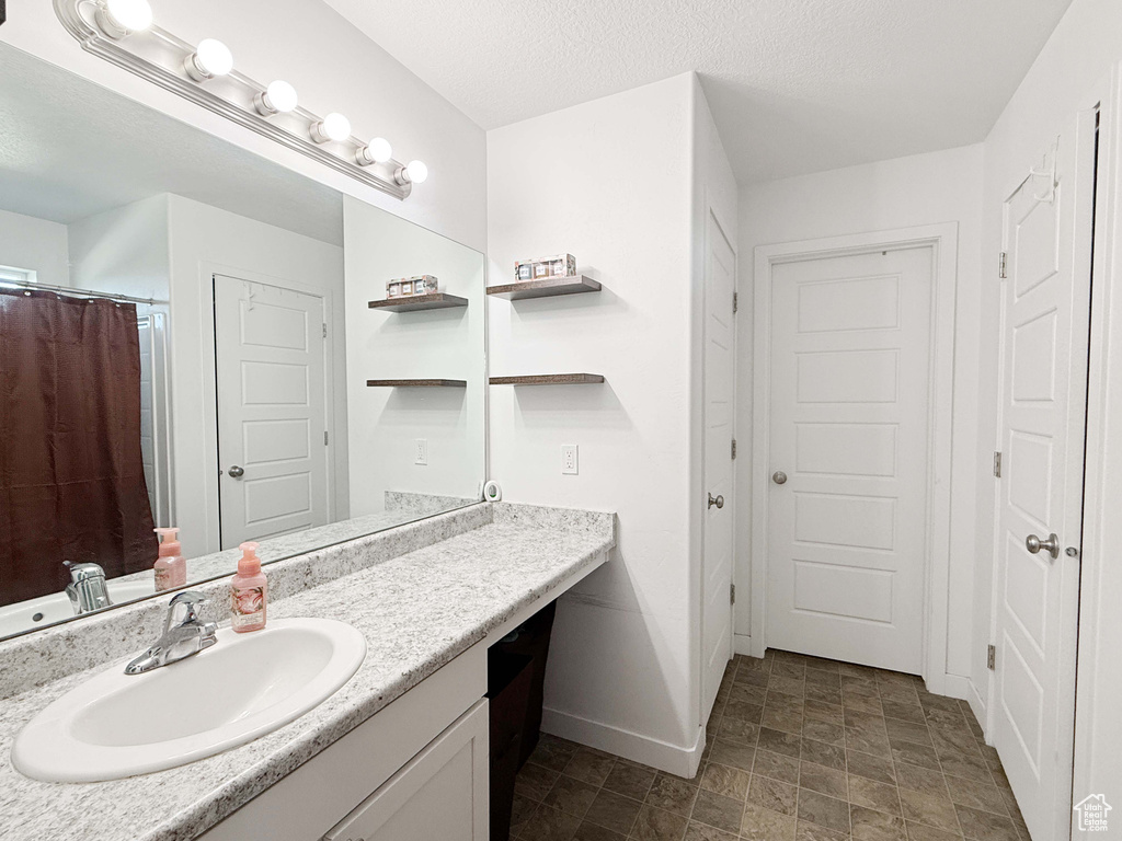 Bathroom featuring baseboards, vanity, and stone finish floors