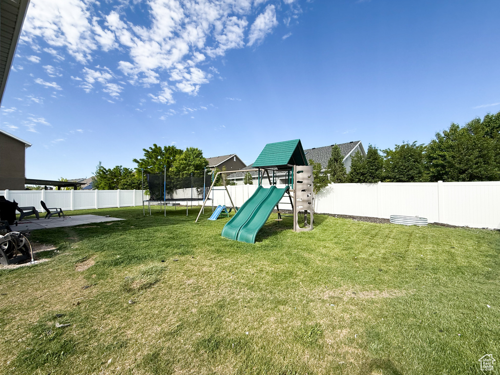 View of yard featuring a playground and a trampoline