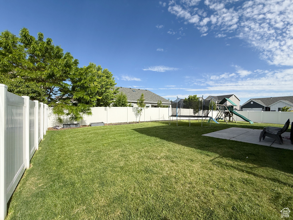 View of yard with a trampoline, a playground, and a patio area