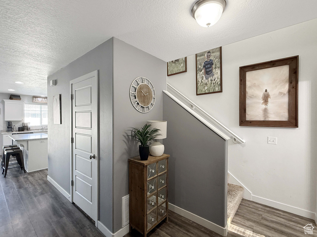 Staircase with a textured ceiling, wood finished floors, and baseboards