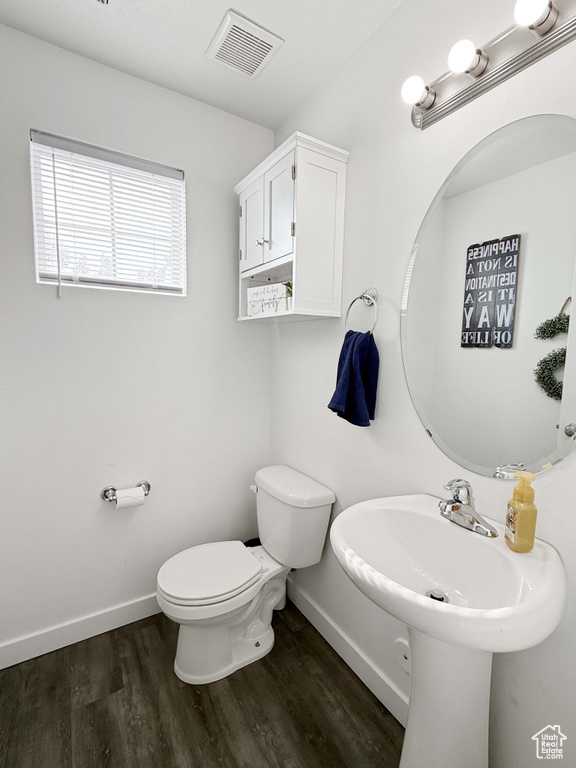 Half bathroom with toilet, wood finished floors, and baseboards