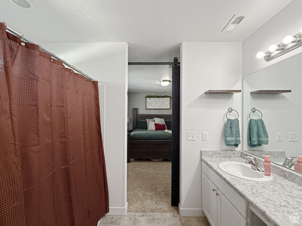 Ensuite bathroom featuring a textured ceiling, vanity, and a shower with curtain