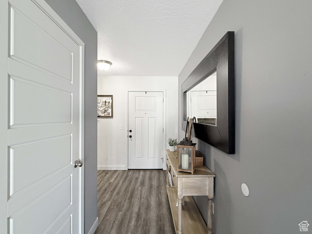 Hallway with baseboards, wood finished floors, and a textured ceiling