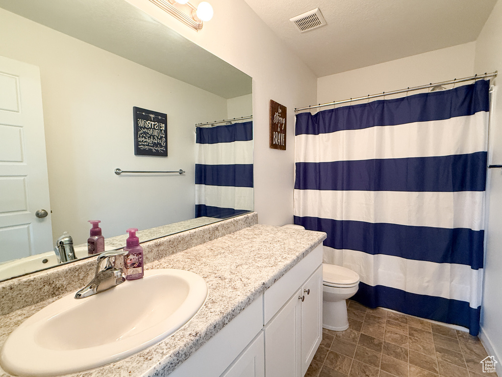 Full bathroom with vanity, toilet, and stone finish flooring