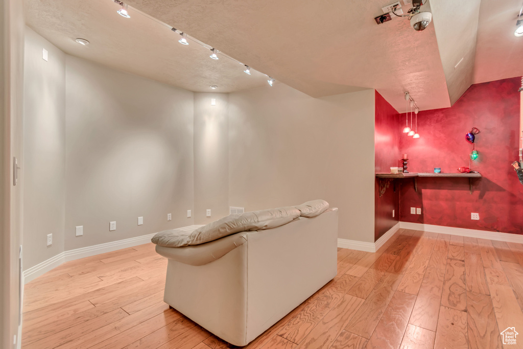Home theater with light wood-style flooring, baseboards, and track lighting