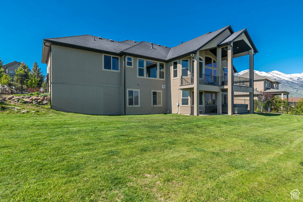 Rear view of house featuring a balcony, stucco siding, and a mountain view