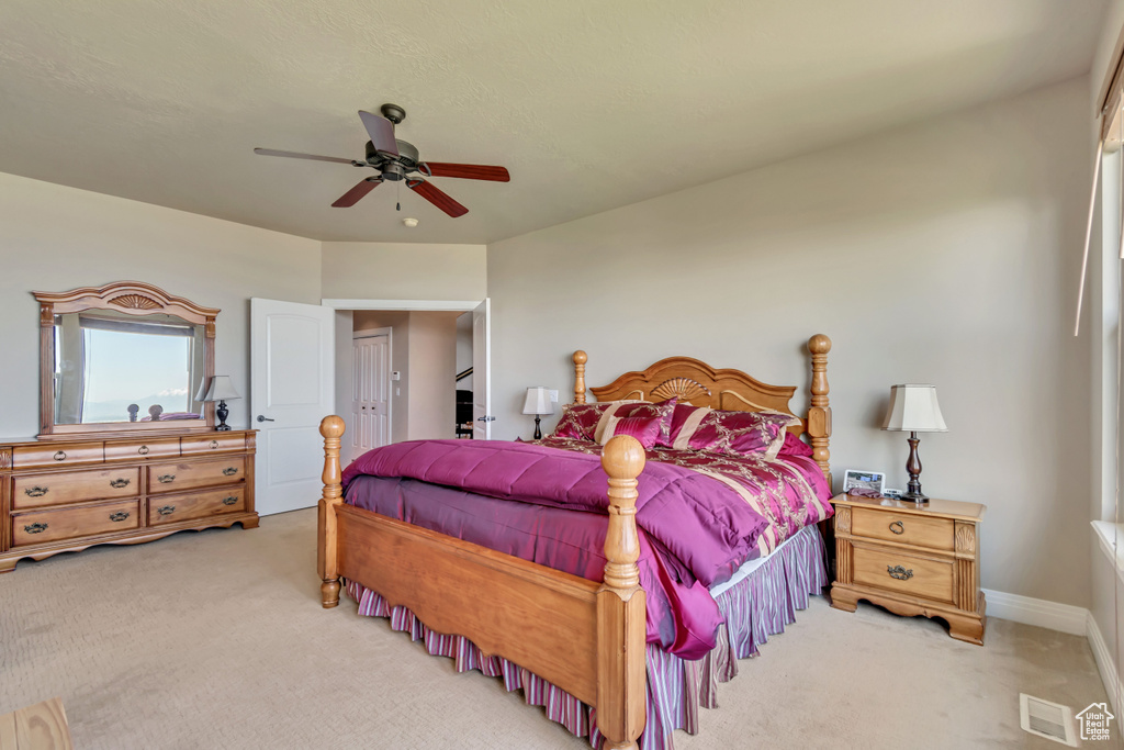 Bedroom with light colored carpet, a ceiling fan, and baseboards