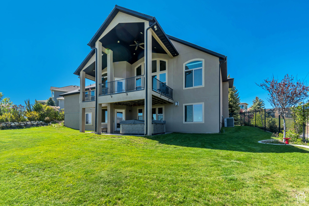 Back of house with stucco siding, a balcony, and cooling unit