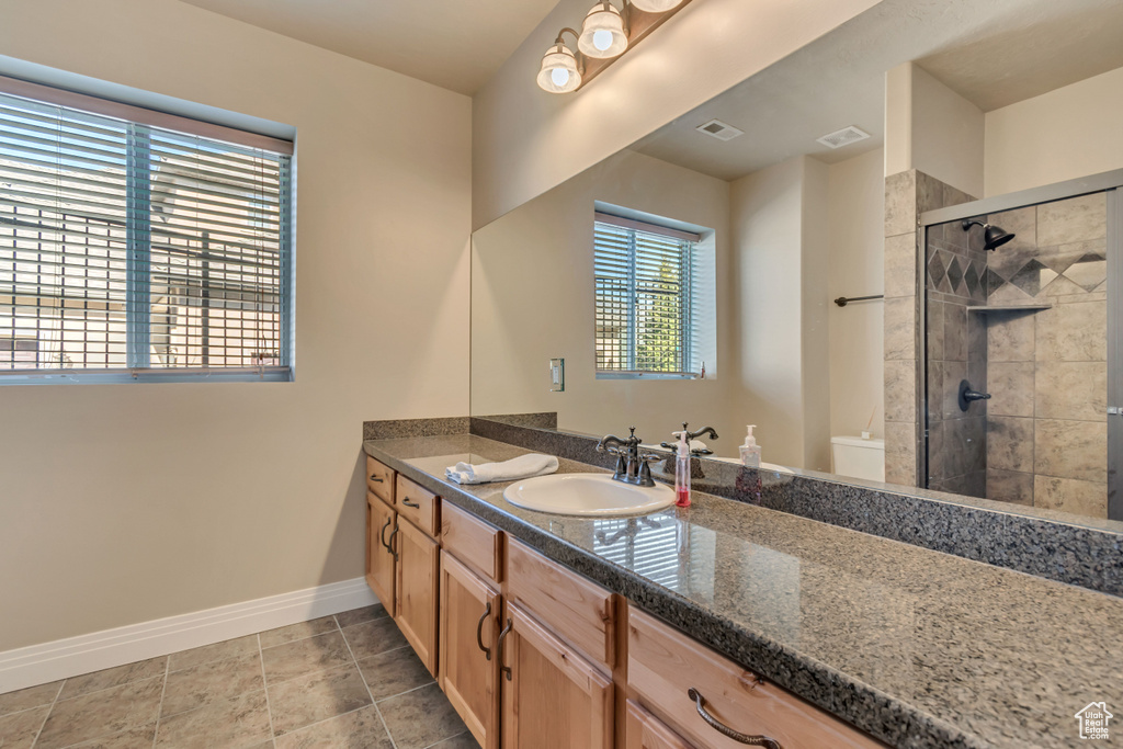 Bathroom with baseboards, vanity, a shower stall, and toilet
