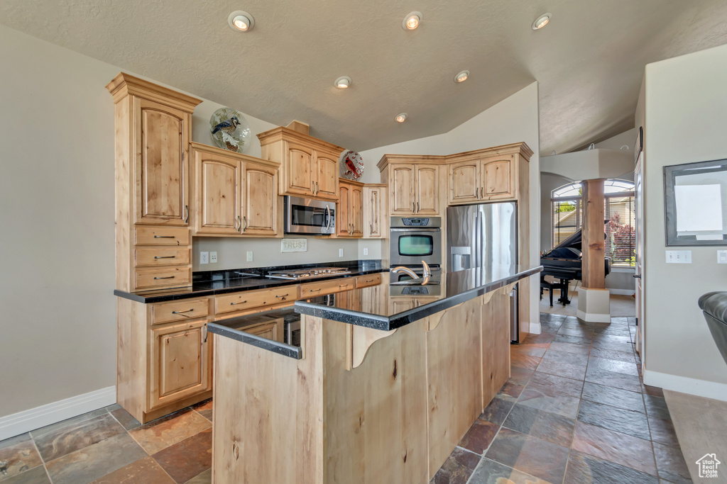 Kitchen featuring appliances with stainless steel finishes, baseboards, light brown cabinets, lofted ceiling, and recessed lighting