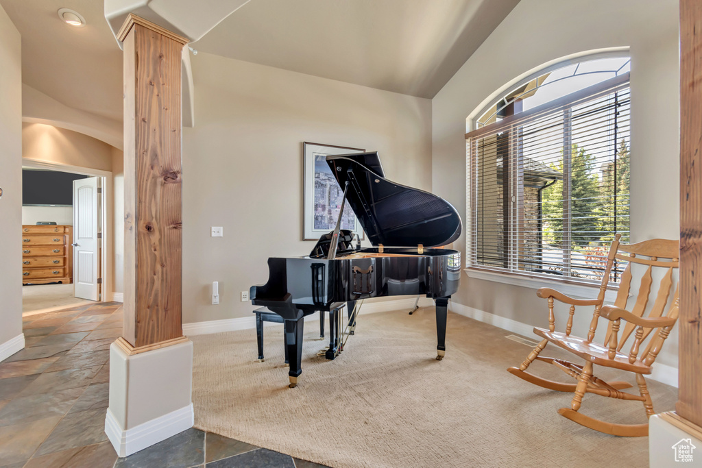 Sitting room featuring lofted ceiling, baseboards, ornate columns, and stone finish floors