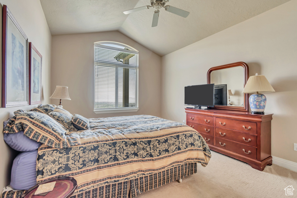 Carpeted bedroom with vaulted ceiling, ceiling fan, and baseboards