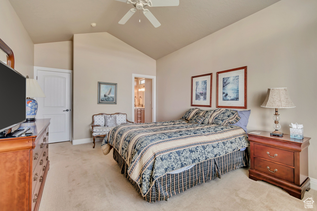 Bedroom featuring light carpet, vaulted ceiling, baseboards, ceiling fan, and ensuite bath