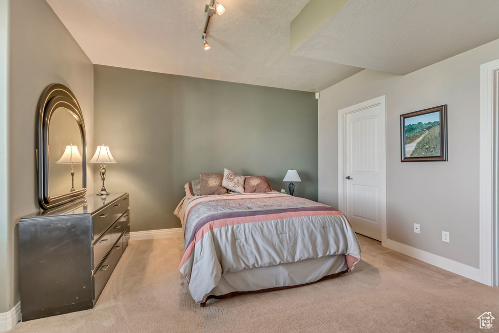 Bedroom with light carpet, baseboards, and track lighting