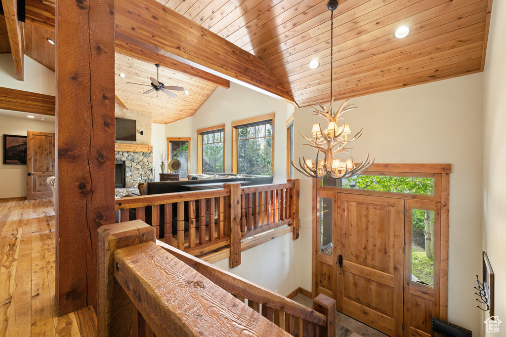 Entrance foyer featuring hardwood / wood-style flooring, recessed lighting, a stone fireplace, a chandelier, and wood ceiling