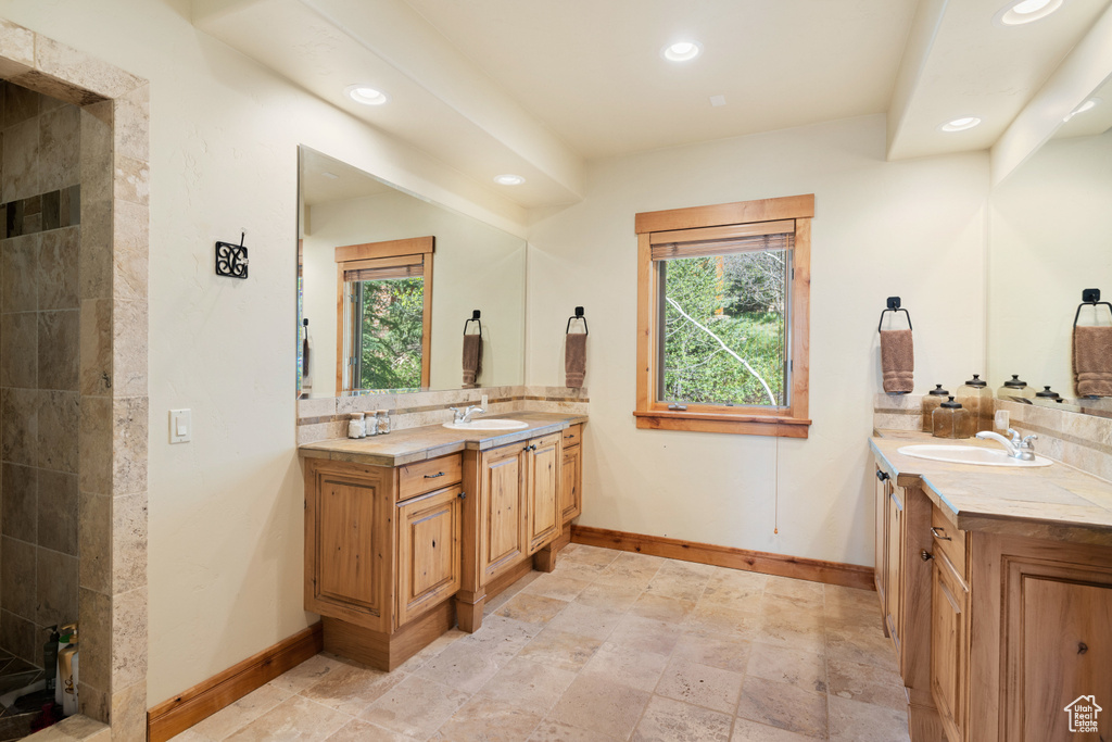 Bathroom featuring two vanities, recessed lighting, baseboards, and backsplash