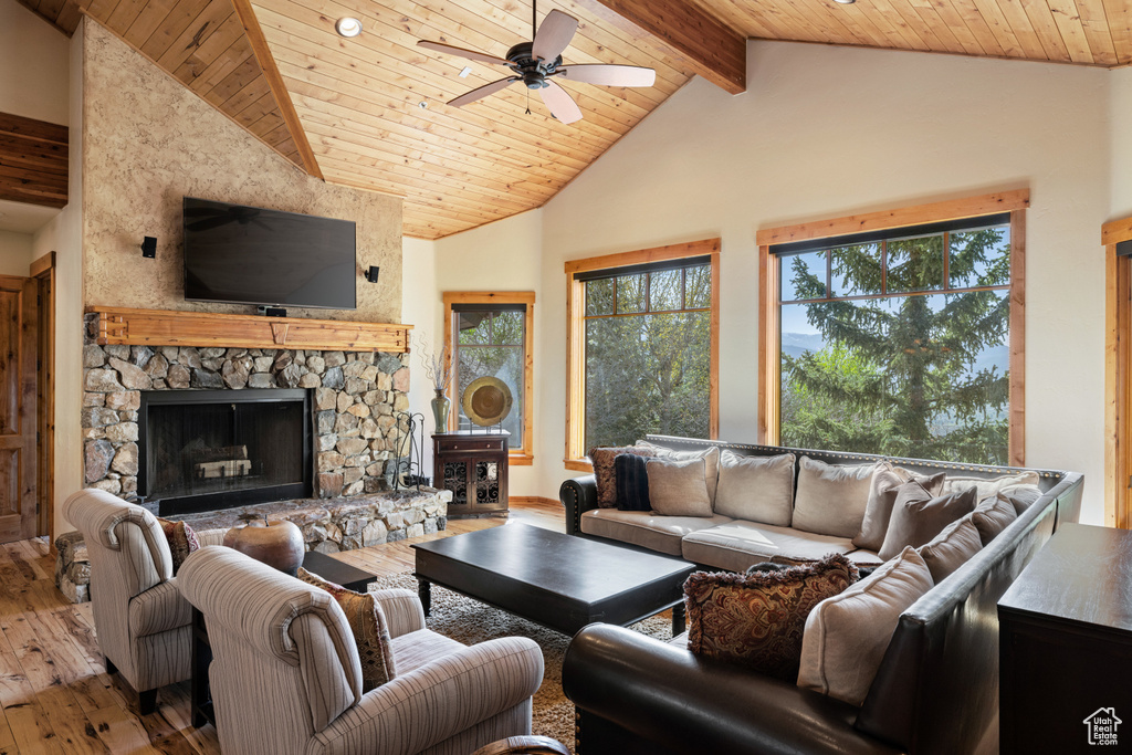 Living room featuring wood-type flooring, ceiling fan, a fireplace, wooden ceiling with exposed beams, and high vaulted ceiling