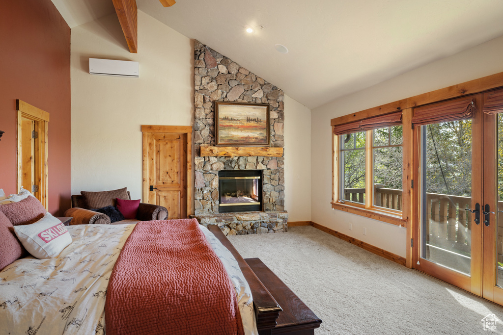 Carpeted bedroom with a wall unit AC, a stone fireplace, access to outside, baseboards, and high vaulted ceiling