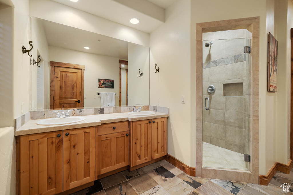 Full bathroom with a shower stall, double vanity, baseboards, and recessed lighting