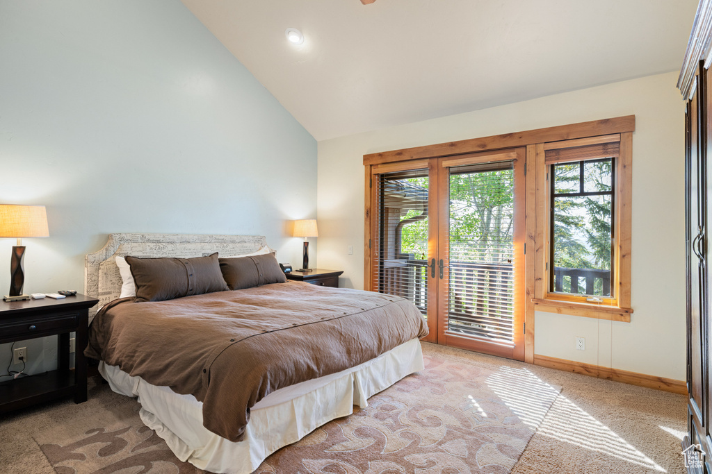 Bedroom with access to outside, multiple windows, light colored carpet, baseboards, and high vaulted ceiling