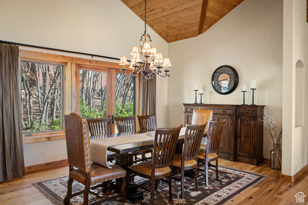 Dining room with wooden ceiling, baseboards, light wood-style flooring, a chandelier, and high vaulted ceiling