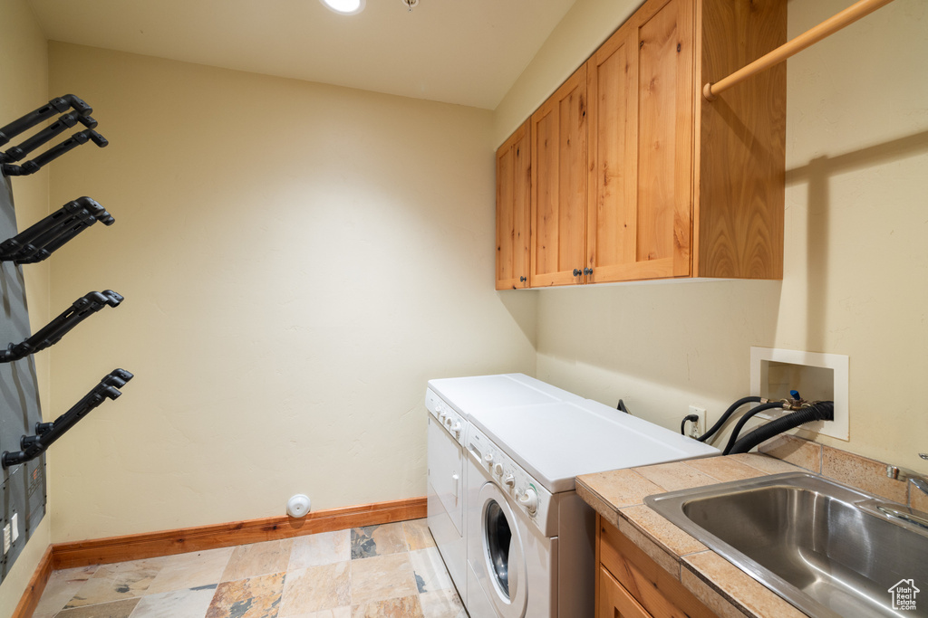 Laundry room with independent washer and dryer, baseboards, cabinet space, and light stone finish flooring