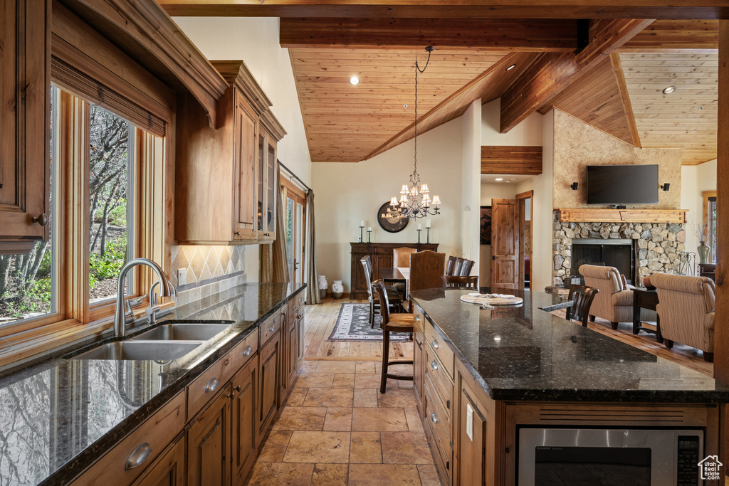 Kitchen with a fireplace, stainless steel microwave, a sink, stone tile floors, and a chandelier