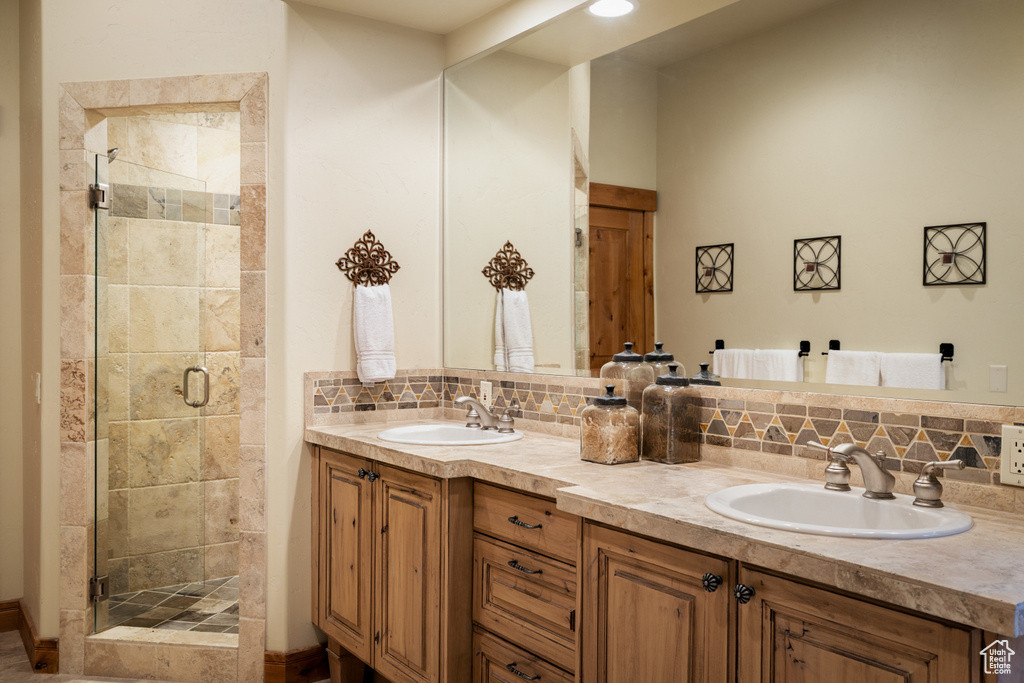 Bathroom featuring tasteful backsplash, double vanity, and a shower stall