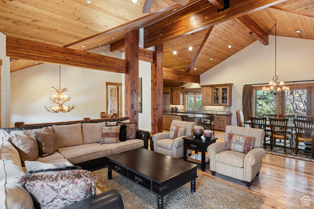 Living room featuring a chandelier, wood ceiling with exposed beams, light wood-style floors, recessed lighting, and high vaulted ceiling