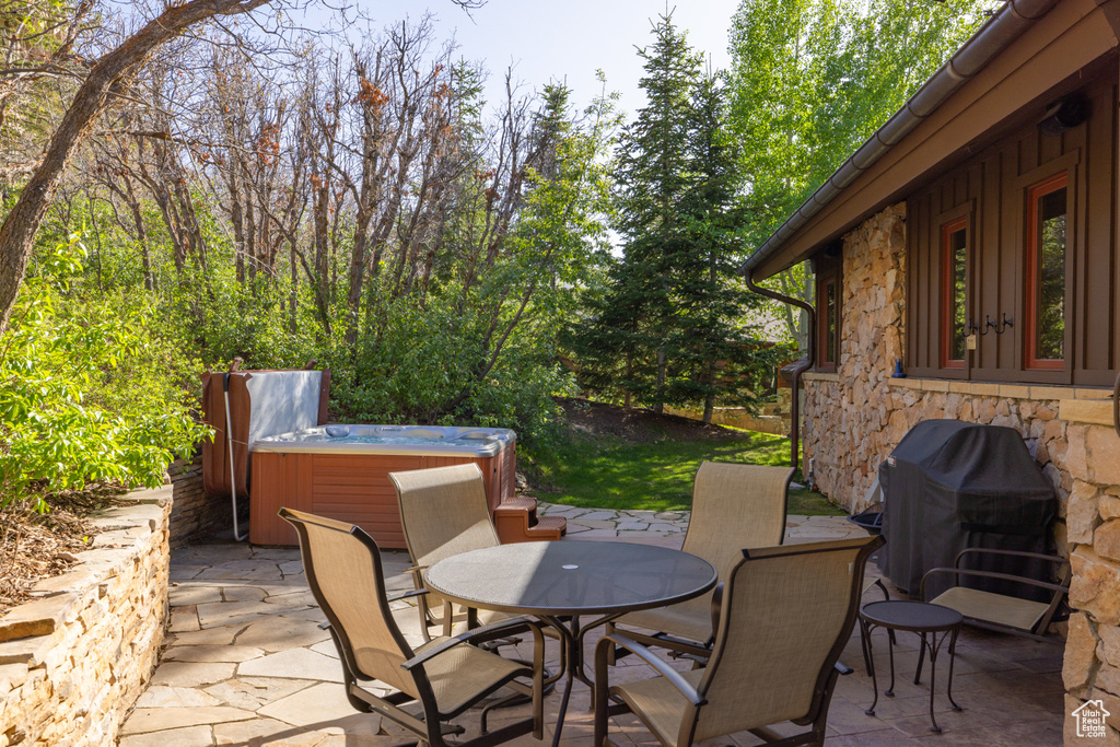 View of patio / terrace with a hot tub, outdoor dining area, and a grill