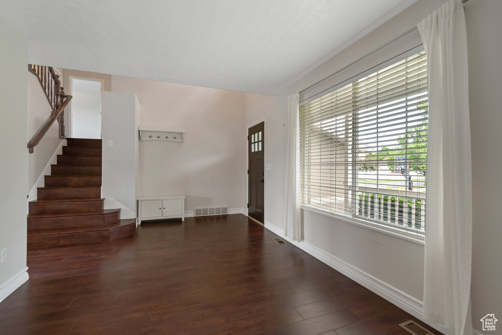 Foyer with stairs, dark wood-style floors, and baseboards