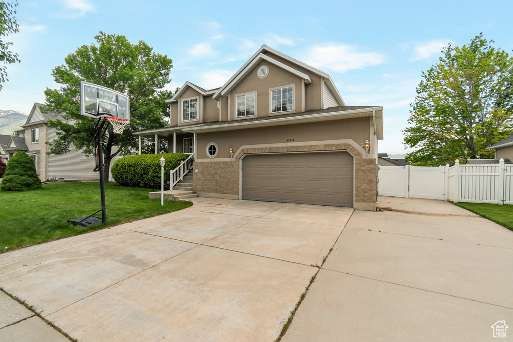 Traditional-style home with a gate, stucco siding, concrete driveway, an attached garage, and brick siding