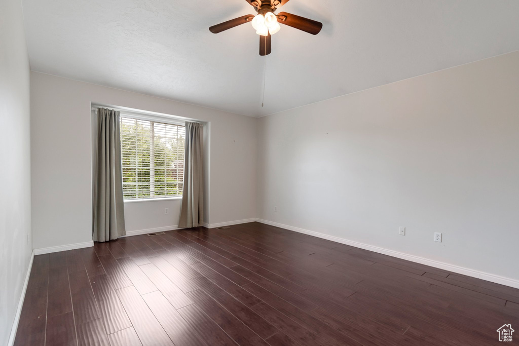 Unfurnished room featuring ceiling fan, baseboards, and dark wood finished floors