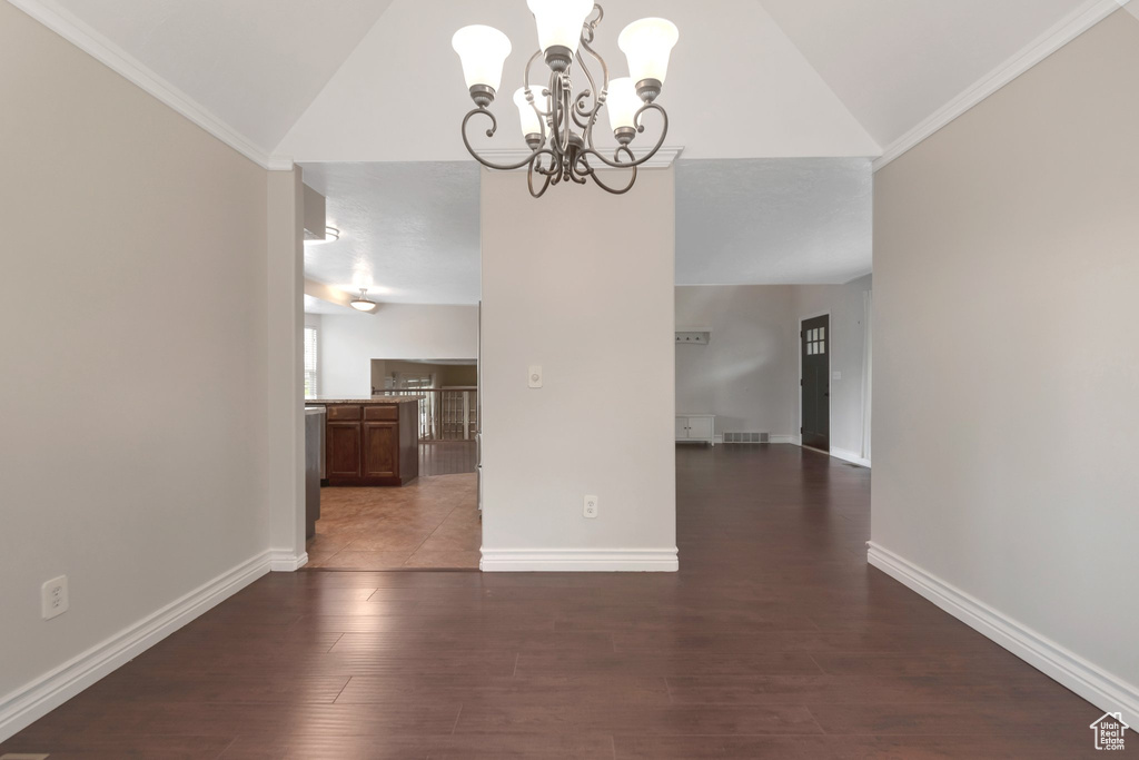 Unfurnished dining area with a chandelier, lofted ceiling, baseboards, and dark wood-type flooring