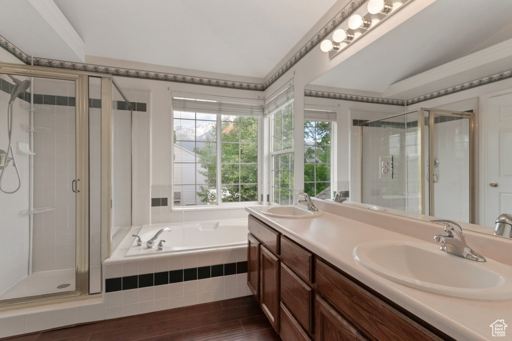 Bathroom with a stall shower, double vanity, a garden tub, and wood finished floors