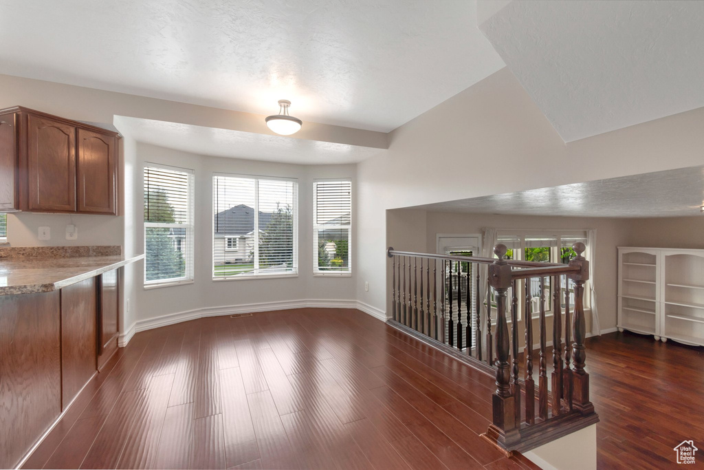 Kitchen with light countertops, dark wood finished floors, baseboards, and brown cabinetry