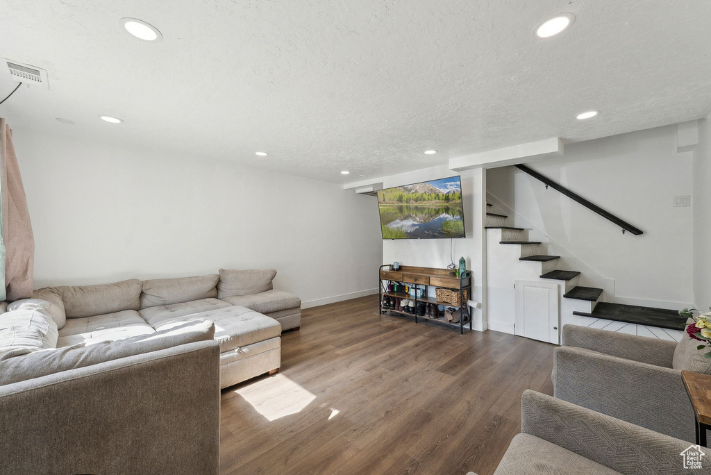 Living room featuring recessed lighting, wood finished floors, baseboards, stairway, and a textured ceiling