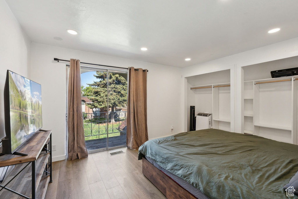 Bedroom with access to exterior, multiple closets, recessed lighting, and wood finished floors