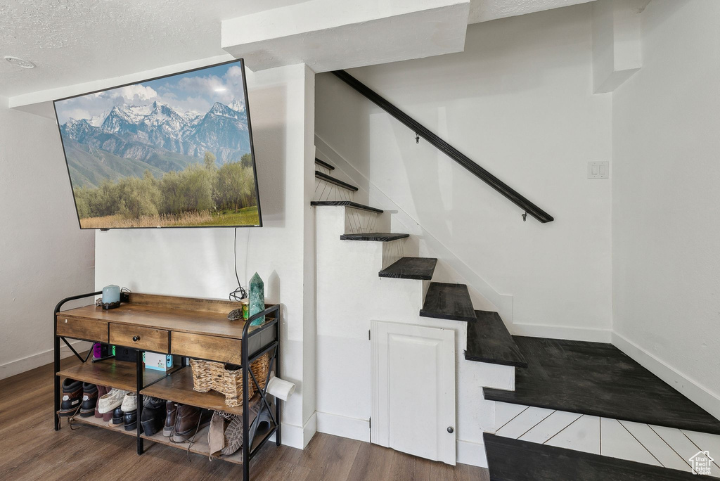 Stairs featuring baseboards, wood finished floors, and a textured ceiling