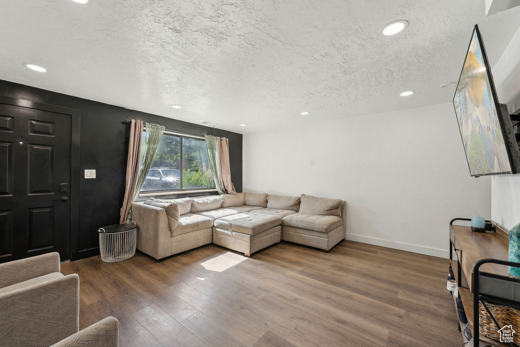 Living room featuring a textured ceiling, wood finished floors, recessed lighting, and baseboards