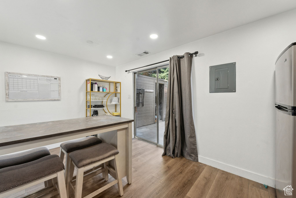 Kitchen with electric panel, light wood-style floors, baseboards, recessed lighting, and freestanding refrigerator