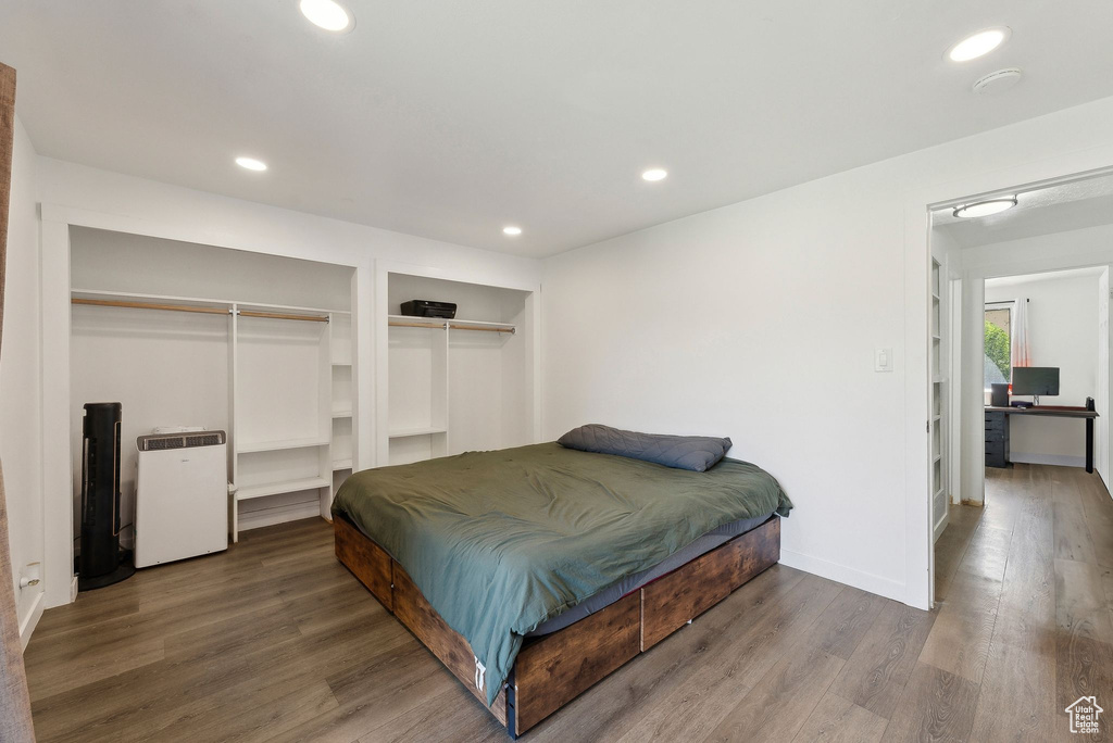 Bedroom with wood finished floors, recessed lighting, multiple closets, and baseboards